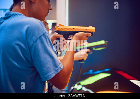 Amis adolescents tir avec des pistolets en une salle de jeux électroniques Banque D'Images