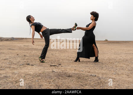 Jeune femme tenant de la jambe dans l'autre femme paysage sombre Banque D'Images