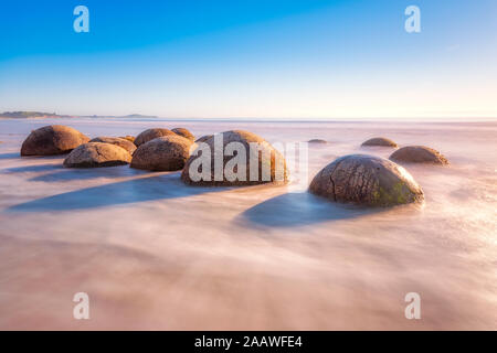 Moeraki Boulders en mer à Koekohe Plage contre sky, Nouvelle-Zélande Banque D'Images