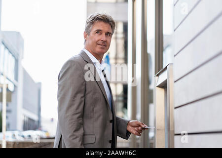 Mature businessman le retrait d'argent à un guichet automatique Banque D'Images