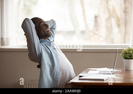 Happy African American Woman relaxing in chair at workplace Banque D'Images