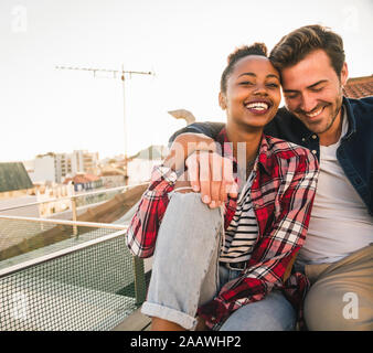 Happy young couple sitting on toit dans la soirée Banque D'Images