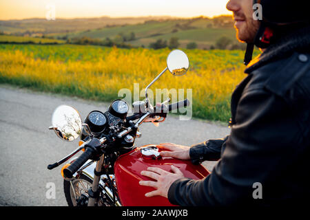 Petit coup de l'homme sur sa moto vintage au coucher du soleil, Toscane, Italie Banque D'Images