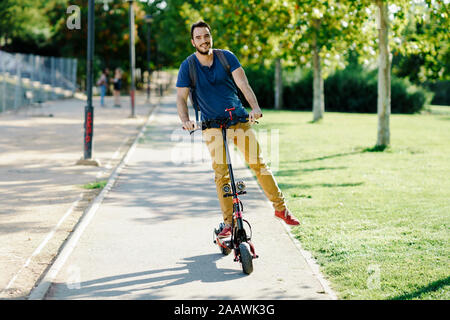 Portrait of smiling man riding scooter électrique Banque D'Images