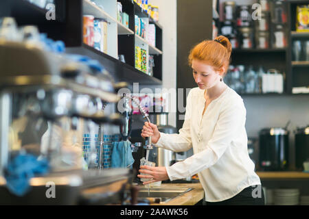 Jeune femme travaillant dans un café, lave-vaisselle Banque D'Images