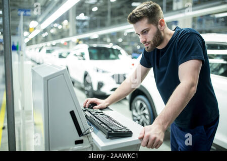 L'homme travaillant sur ordinateur en usine automobile moderne Banque D'Images