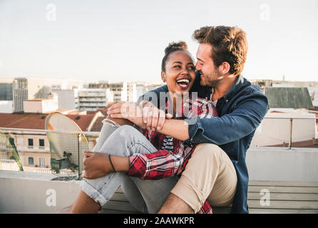 Happy young couple sitting on toit dans la soirée Banque D'Images