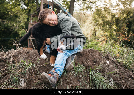 Garçon jouant avec son chien de Montagne bernois dans le jardin Banque D'Images