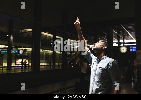 Homme à la gare dans l'ombre regardant vers le haut et pointant son doigt, Berlin, Allemagne Banque D'Images