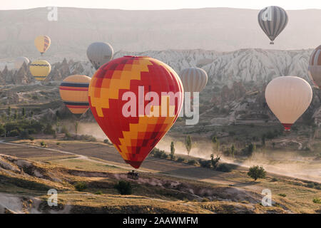 Montgolfières multicolores voler au-dessus de terres à parc national de Göreme pendant le coucher du soleil, Cappadoce, Turquie Banque D'Images