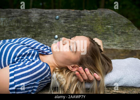 Femme se détendre sur un banc en bois Banque D'Images