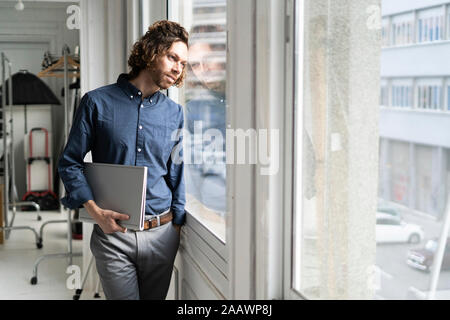 Man holding dossier dans un studio à la fenêtre de Banque D'Images