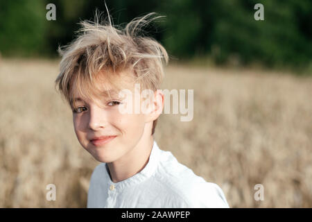 Portrait of smiling blonde boy dans un champ d'avoine Banque D'Images