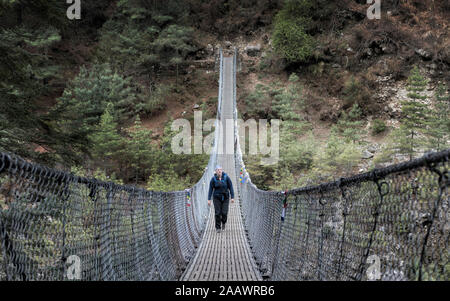 Jeune femme traversant le pont suspensio Phakding, Solo Khumbu, Népal Banque D'Images