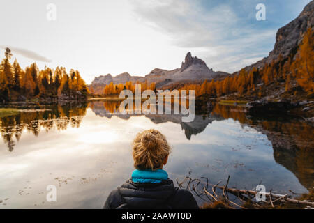 Female hiker regardant le paysage de montagne avec lac à la première lumière du jour, Alpes Dolomites, Cortina, Italie Banque D'Images