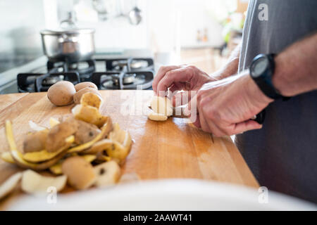 Coupe homme Senior pommes de terre sur la planche à découper Banque D'Images