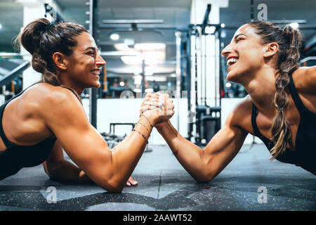 Heureux les jumeaux en bonne forme faisant Arm wrestling challenge dans une salle de sport Banque D'Images