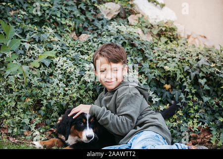 Garçon jouant avec son chien de Montagne bernois dans le jardin Banque D'Images