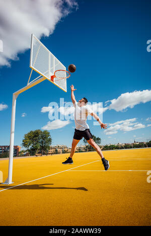 L'homme jouant au basket-ball sur cour jaune, tremper Banque D'Images