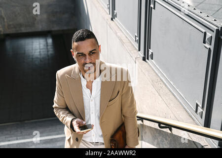 Portrait of businessman avec écouteurs et de la station de métro laissant smartphone Banque D'Images