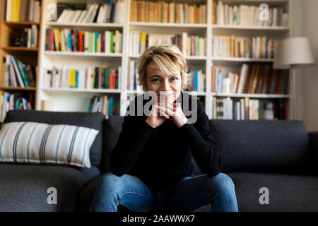 Portrait of smiling mature woman sitting on sofa at home Banque D'Images