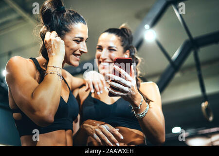 Female jumeaux en bonne forme en utilisant smartphone dans une salle de sport Banque D'Images