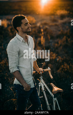 Jeune homme avec son vélo de course en soleil Banque D'Images