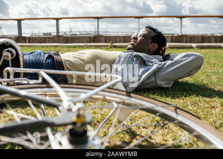 Jeune homme à la location, de détente, allongé sur l'herbe Banque D'Images