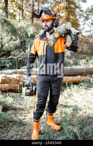 Portrait d'un marchand de vêtements de protection professionnelle en avec une tronçonneuse et en bois de sciage au cours des travaux sur l'exploitation forestière dans la forêt de pins Banque D'Images