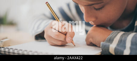 Dessin au crayon d'étudiants sur l'ordinateur portable. Boy doing homework écrit sur un papier. Kid tenir un crayon et dessiner un manga à la maison. Une séance de dessin de l'adolescence Banque D'Images