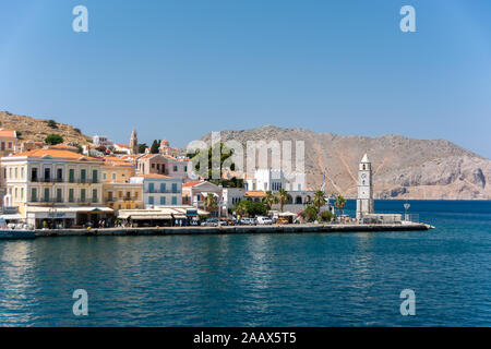 SYMI, GRÈCE - 25 juin 2019 : Bay, tour de l'horloge, et de vieux bâtiments sur une île grecque Symi Banque D'Images