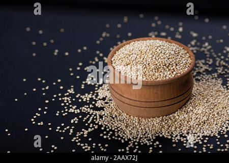 Les graines de quinoa dans bol en bois sur fond noir Banque D'Images