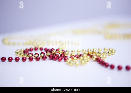 Différentes perles colliers sur table en bois blanc. Maison de vacances. Noël. Nouvelle Année. différentes couleurs - rouge, jaune . La structure horizontale. Soft focus Banque D'Images