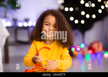 Cute girl africaine cadeau de Noël d'ouverture à la maison Banque D'Images