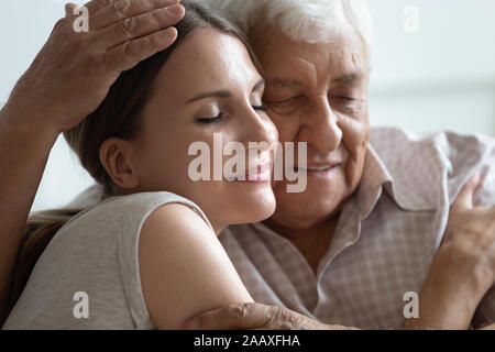 Pycnanthème gris âgés man hugging aimer grandi fille à la maison. Banque D'Images