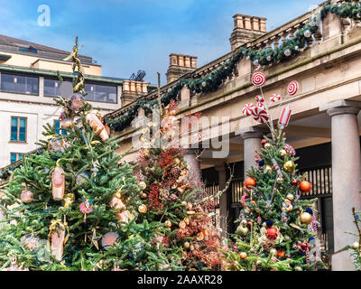 Les arbres de Noël à l'extérieur dans Covent Garden Market Place agrémentée d'ornements colorés et voyants à Londres, Royaume-Uni Banque D'Images
