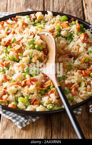 Riz frit aux légumes et bacon close-up dans une assiette sur la table verticale. Banque D'Images