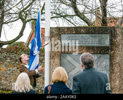 Athelstaneford, East Lothian, Écosse, Royaume-Uni. 24 novembre 2019. Festival de la Saltire : le premier jour du festival annuel de la St Andrew a lieu dans le lieu de naissance du drapeau national écossais où la saltire est apparue dans le ciel comme un bon présage. Après un service de l'église, le ministre bénit le nouveau Saltyre que Fraser Thompson du Scottish Flag Trust soulève au Mémorial Banque D'Images