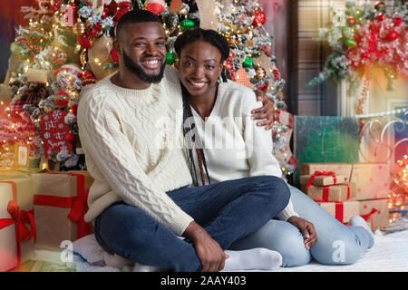 Cheerful black couple posant près de l'arbre de Noël, célébrer Noël ensemble Banque D'Images