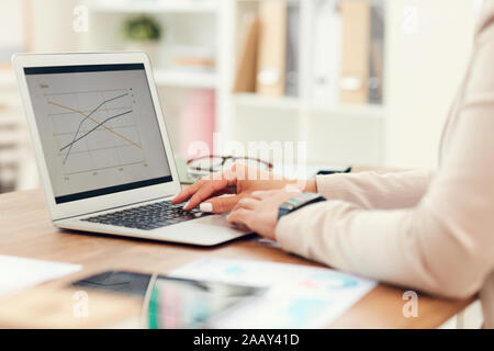 Side view close up of businesswoman méconnaissables à l'analyse de données statistiques graphiques while using laptop in office, copy space Banque D'Images