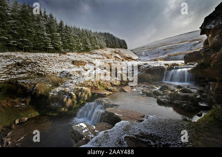 Ruisseau de montagne avec de petites chutes de neige de l'hiver et ciel dramatique
