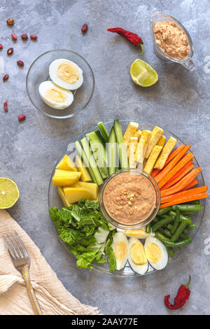 Mise à plat avec indonesian gado-gado salade avec sauce aux cacahuètes sur fond de béton gris Banque D'Images