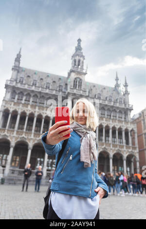 Une femme prend des photos sur son téléphone contre la toile du musée de la ville de Bruxelles sur la place principale Grand place à Bruxelles, Belgique Banque D'Images