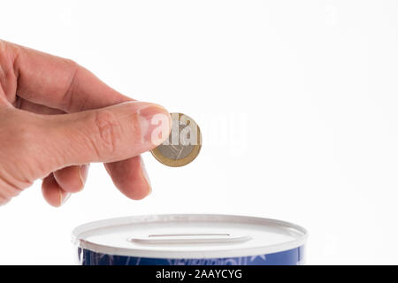 Homme de main de mettre une pièce dans tin can banque d'épargne. Close-up d'un euro dans la main. Banque D'Images