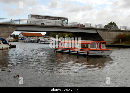 Motor Cruiser Acle en passant sous le pont de la rivière Bure, Norfolk Broads, l'Angleterre, avec l'entraîneur passant sur Banque D'Images