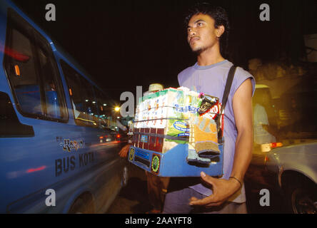 L'Indonésie. Sulawesi. Manado city street at night. Vente homme boire en carton. Banque D'Images