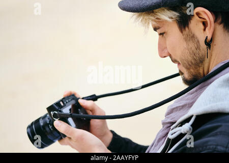 Hipster Photographe de rue l'examen de photos sur l'écran de l'appareil photo Mirrorless Banque D'Images