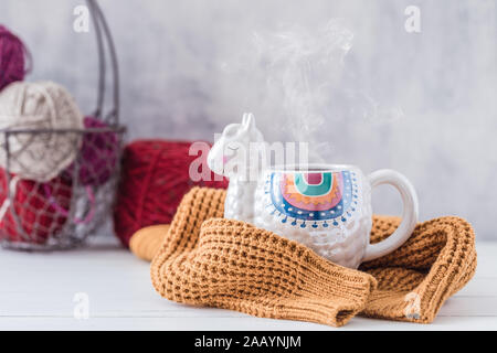 Mug en forme de Lama colorés avec pull tricoté sur la table en bois blanc, teinté Banque D'Images