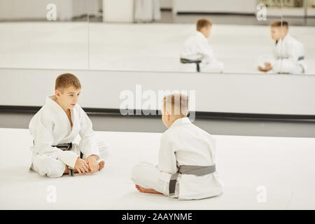 Deux garçons en kimono blanc assis sur le sol en face de l'autre ils discutent de leur futur concours Banque D'Images