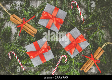 Trois cadeaux de Noël assis sur les branches d'un arbre de Noël aux côtés de canne et bâton de cannelle decorations Banque D'Images